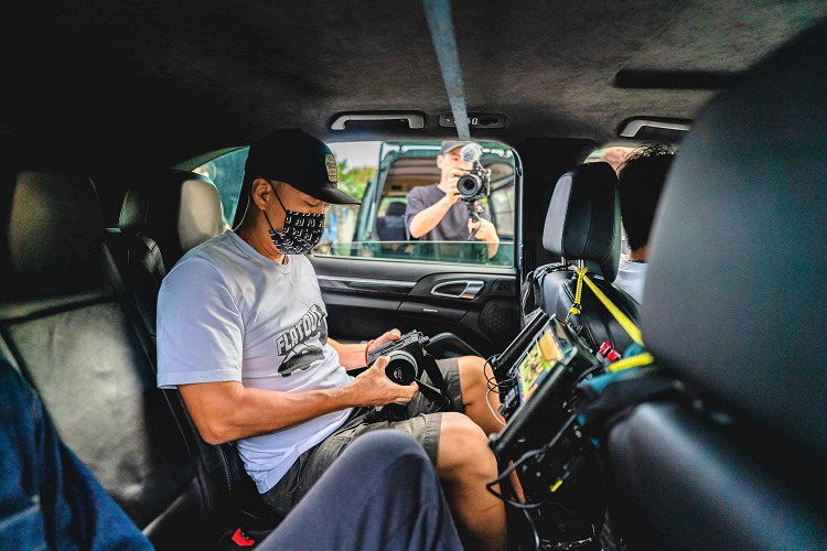攝影師坐在跟拍車內看著螢幕控制鏡頭捕捉商品車畫面，看似簡單的操作卻具有技術含量。